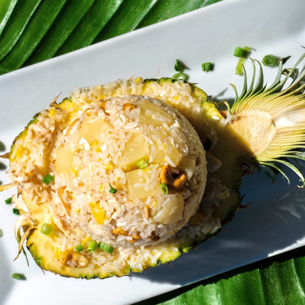 Thailicious pineapple fried rice, served in a pineapple half, garnished with cashews and green onions.