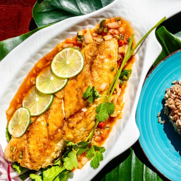 Thailicious' whole fish dish with lime slices, cilantro, and a side of rice.
